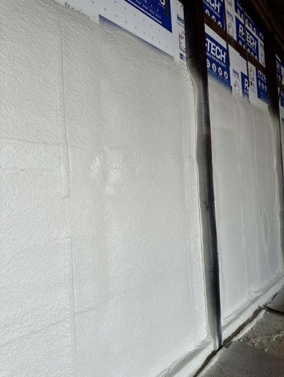 White spray foam insulation applied smoothly on wall panels with black framing.